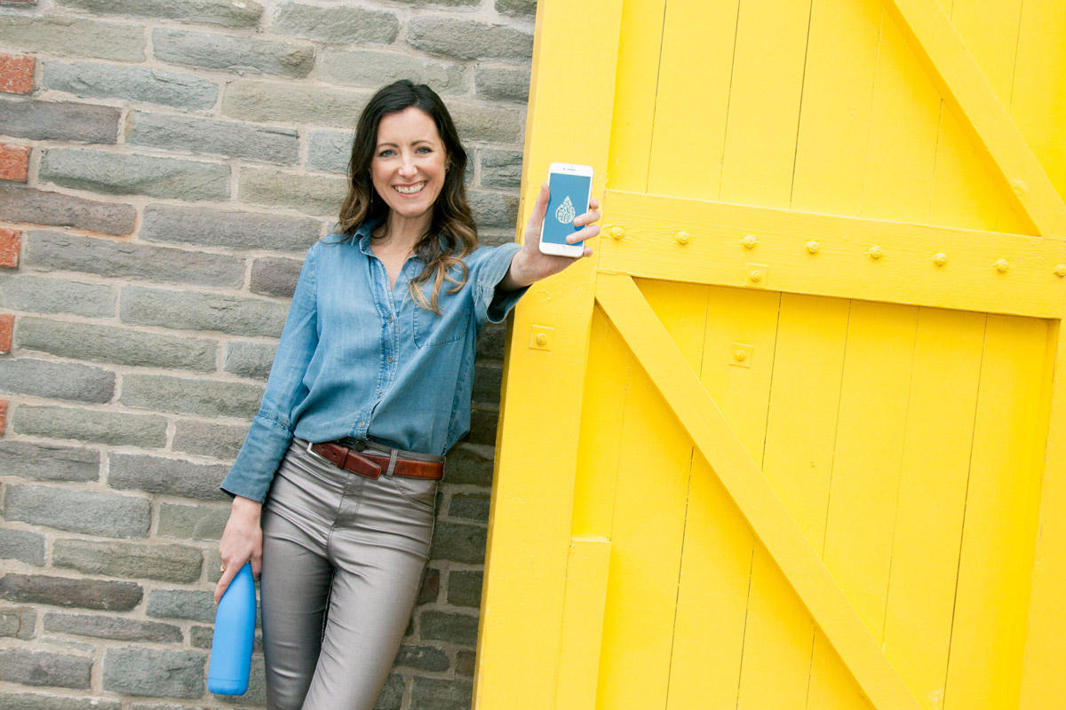 A woman holding a phone showing the refill app by City to Sea, UK