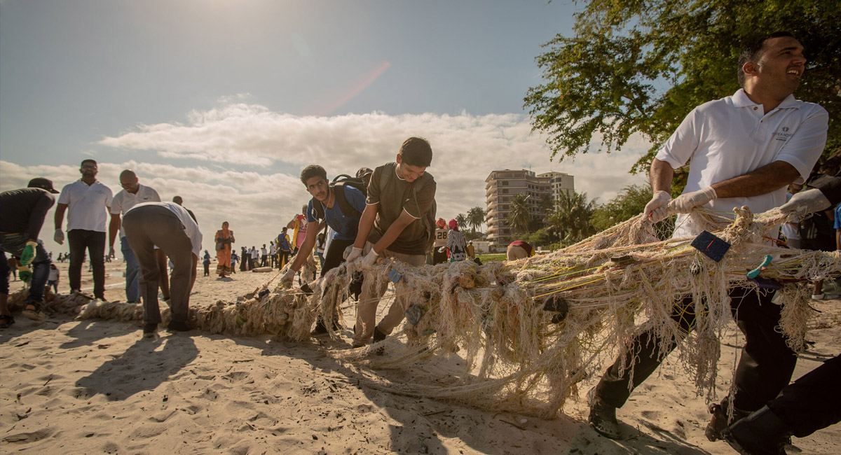 A group of male participants during the World cleanup day in Tanzania are pulling a long string of trash